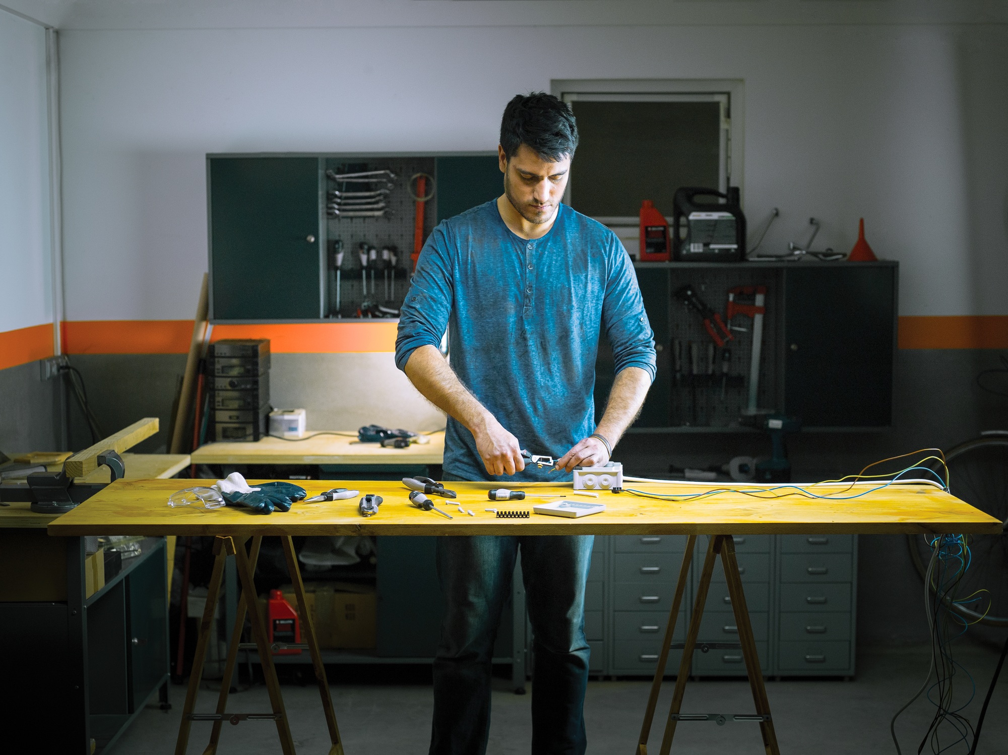 A man performs some electrical repairs in the garage of his house.