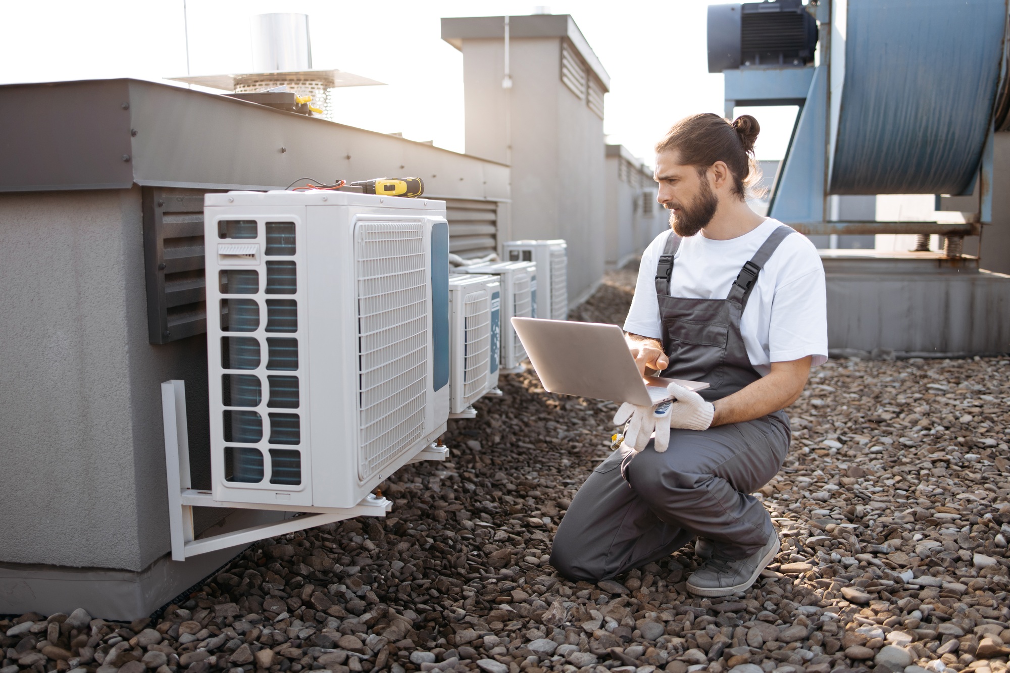 Man worker using laptop and servicing conditioner outdoor