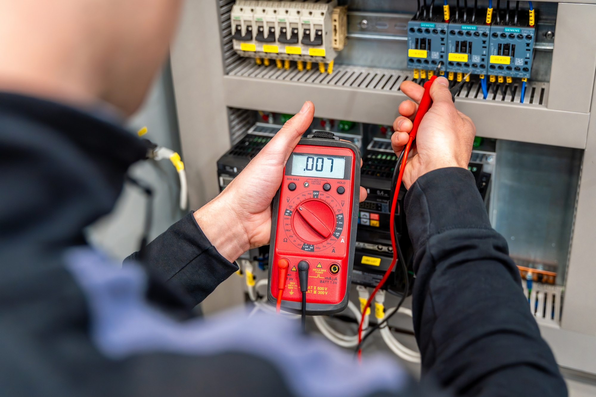 Worker measuring and repairing an electrical system panel